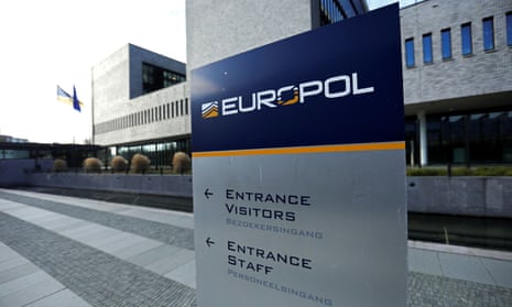 Photo of squared-off, modern Europol building in the Hague, with blue and yellow Europol sign in the foreground