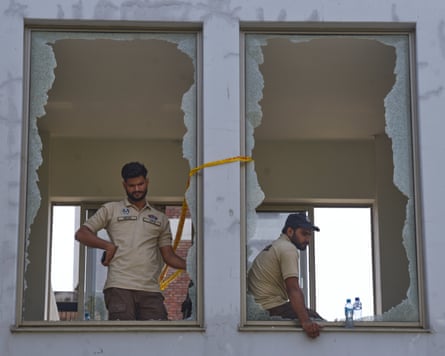 Two police officers looking from two broken windows