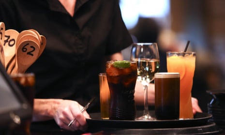 A staff member prepares to carry a tray of drinks to a customer in a pub