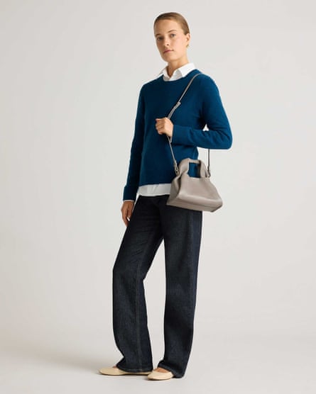 woman wearing blue sweater, jeans and a gray purse on shoulder