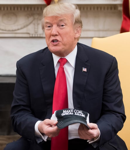 President Donald Trump holds a hat that says, “Make Coal Great Again,” during a meeting discussing tax reform in the Oval Office of the White House in Washington, DC in 2017.