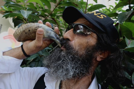Close up of man blowing horn with beard and sunglasses