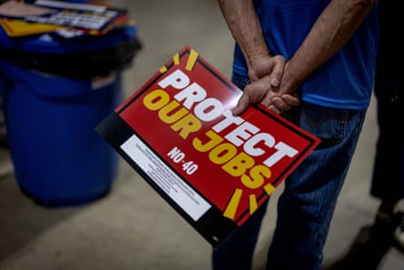 A rally attendee holds a red “Protect Our Jobs” sign opposing Proposition 40