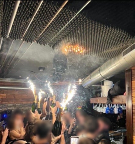 People holding champagne bottles with sparkers, while the ceiling is alight. Identifying personal details have been blurred