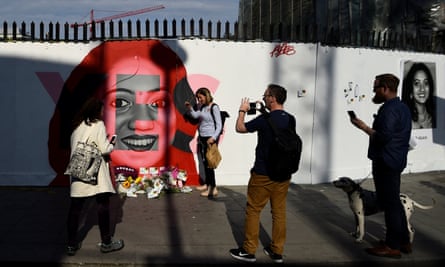 People gather around as flowers are left at the foot of a new mural of Savita Halappanavar.