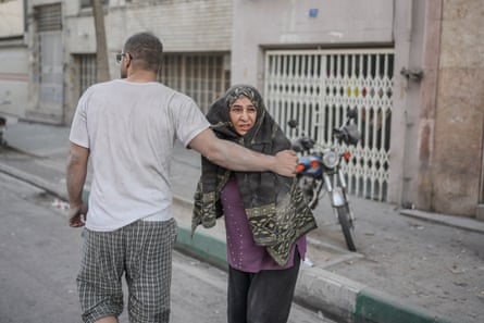 A man, facing the opposite way, puts an arm around a woman who is looking down the street