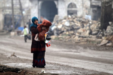 A woman carries a child in the ruined streets of al-Rai north of Aleppo .
