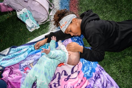 A girl caresses a baby’s face on a flag football field