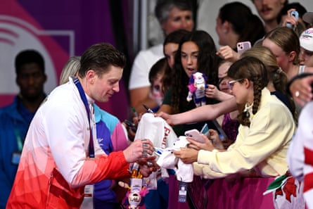 Bronze medalist Adam Ramsay-Peaty of England signs autographs for fans after the men's 100m breaststroke medal ceremony.