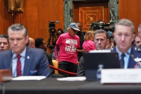 Protesters leave the Senate hearing room as Hegseth speaks.