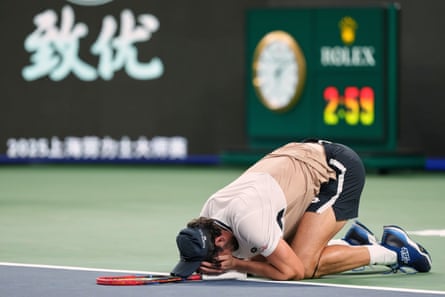Valentin Vacherot crouches on the court with his face in his hands after defeating Holger Rune in Shanghai