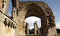 Ruins of Glastonbury Abbey, with one porchway framing two towers in the background