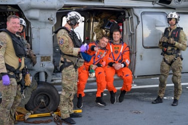 Astronotlar Reid Wiseman ve Jeremy Hansen, USS John P Murtha gemisinin uçuş güvertesinde, bir Donanma MH-60 Seahawk helikopterinde otururken tepki veriyorlar.