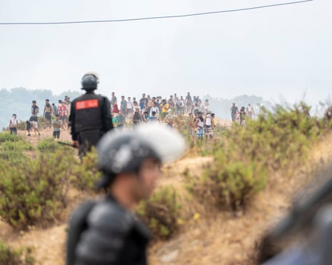 Members of the Moroccan security forces and civilians who returned from Spain gather at the site of clashes at the Bab Sebta border crossing near Fnideq, Morocco across from Ceuta, Spain.