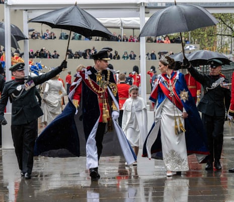 Prince William, Princess Charlotte of Wales and Catherine, Princess of Wales are given an umbrella escort.