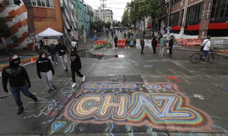 People walk past street art that reads ‘Welcome to Chaz’ inside what is being called the ‘Capitol Hill Autonomous Zone’ in Seattle.