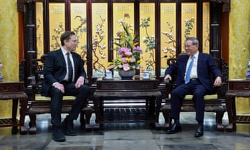 Tesla founder and CEO Elon Musk, left, dressed in dark suit and white shirt and tie, sits at a table with besuited Chinese Premier Li Qiang (right) in Beijing