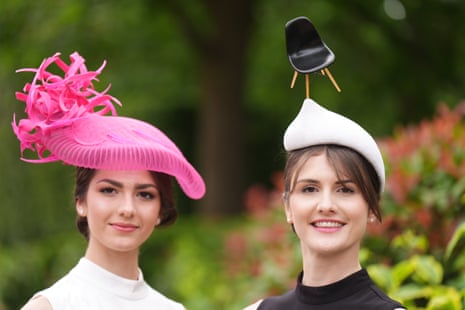 Two racegoers, one with a chair on her hat, right, at Royal Ascot.
