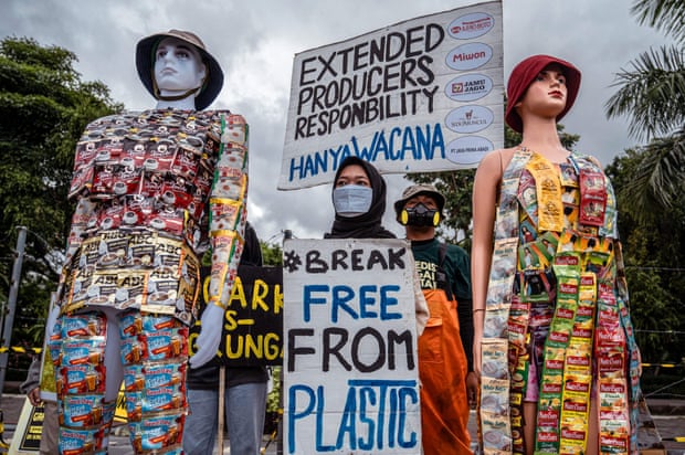 Indonesian environmental activists display banners next to models wearing plastic waste during a campaign against climate change marking 