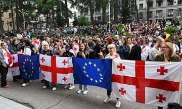 A crowd of protesters holding Georgian and EU flags