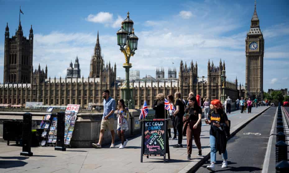 People pass a sandwich board advertising ice cold drinks on Westminster Bridge