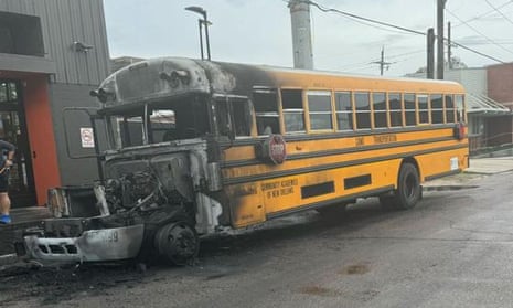 School bus with front end charred and completely burned off, parked on a street.