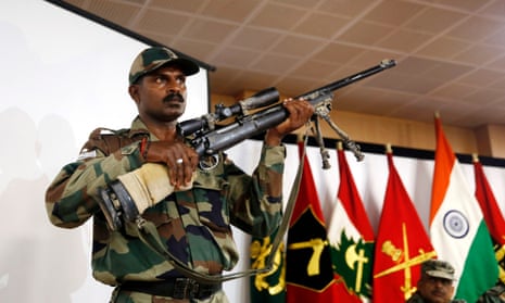 An Indian soldier displays a US-made sniper rifle recovered along with a Pakistani-made mine after searches in the region