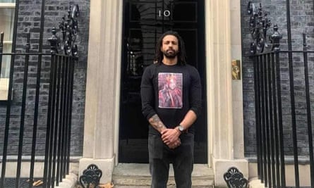 Mohannad Bashir stands on the steps of No 10 Downing Street, with a beard, dreadlocks and hands clasped in front of him and wearing a T-shirt with an image of his brother who died after police restraint