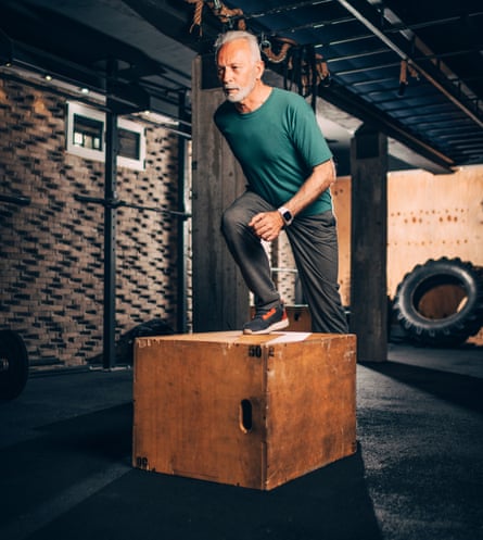 A man stepping onto a wooden box at the gym.