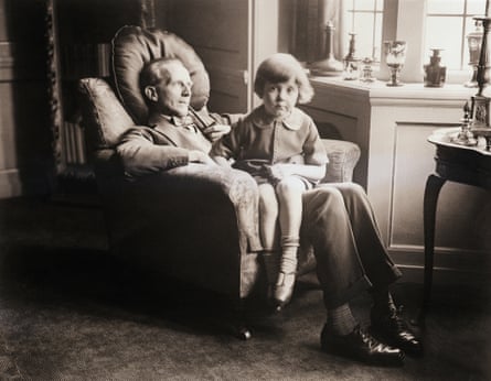 An old black-and-white photograph of a young boy sitting on a man’s lap in a sitting room