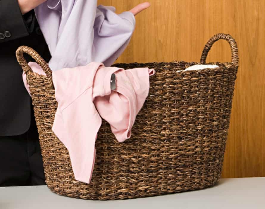 A laundry basket with a pink shirt on one side