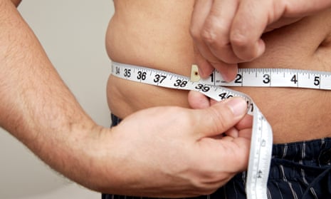 Close-up of a man measuring waist with tape measure.