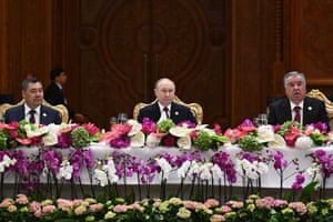 Kyrgyz President Sadyr Japarov, Russian President Vladimir Putin and Tajik President Emomali Rahmon sit at a table decorated with pink flowers