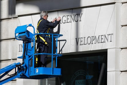 A man in a cherry picker removes signage from the outside of a building