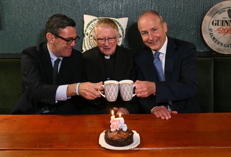 Andy Burnham, left, and Ireland's PM Micheál Martin, right, sit beside Canon Patrick J MacNally on his 90th birthday during a visit to the Brian Boru Irish Club in Ashton-in-Makerfield.