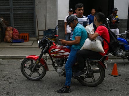 Un hombre lleva un saco de café en la parte trasera de una motocicleta.