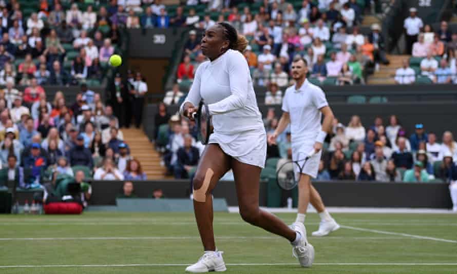 Venus Williams plays a backhand as partner Jamie Murray looks on