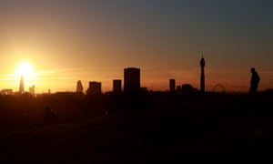 A man watches the sun rise over the city’s skyline from Primrose Hill in London.