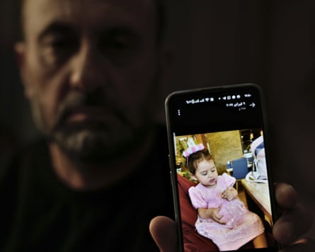 Bassam al-Khatib holds out a photo of his two-year-old granddaughter Layla on his phone screen
