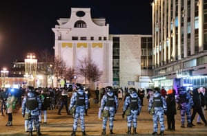 A cordon of police officers watches an anti-war protest in Moscow.