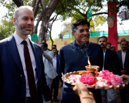 they smile as someone holds out a gold tray with pink flowers and candles on it towards them.