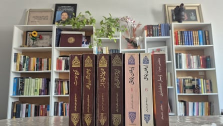 كتب ورقية للرواية مرتبة في المقدمة، مع رفوف بيضاء مملوءة بالكتب وراءها
