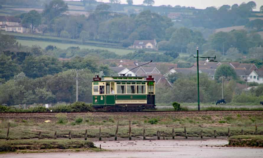 A green tram travels along the Seaton tramway on its way to Colyford.