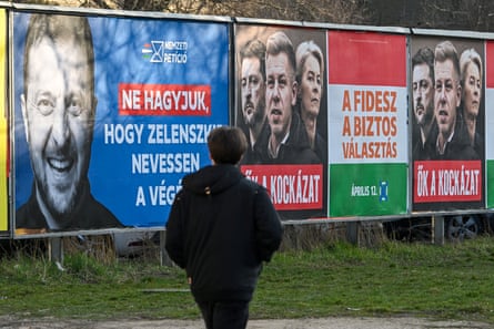 A woman walks past a billboard featuring a portrait of Zelenskyy and another featuring the European Commission president. Ursula von der Leyen, Zelenskyy and Peter Magyar.