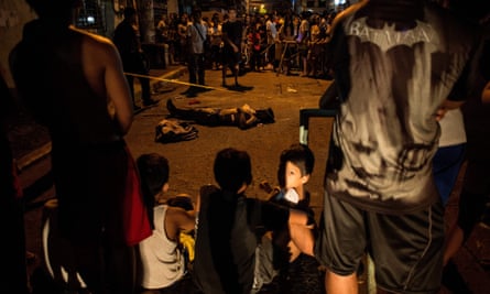 Local residents gather around the body of an alleged drug user, killed by unidentified assailants, in Manila in 2017