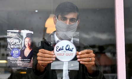 Rishi Sunak places an ‘eat out to help out’ sticker in the window of a business during a visit to Rothesay on the Isle of Bute, Scotland.