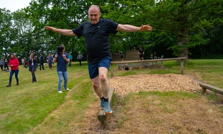 Ed Davey balances on a wooden beam as part in an assault course during a visit to Arena Pursuits in Wadhurst