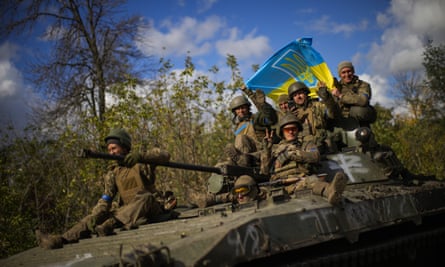 Ukrainian soldiers sit on an armored vehicle as they drive on a road between Izium and Lyman in Ukraine