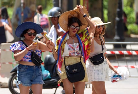Three women in sunglasses, shorts and sunhats parade along Mondello beach