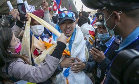 Cheering people greet Purja, with one person handing him a scarf